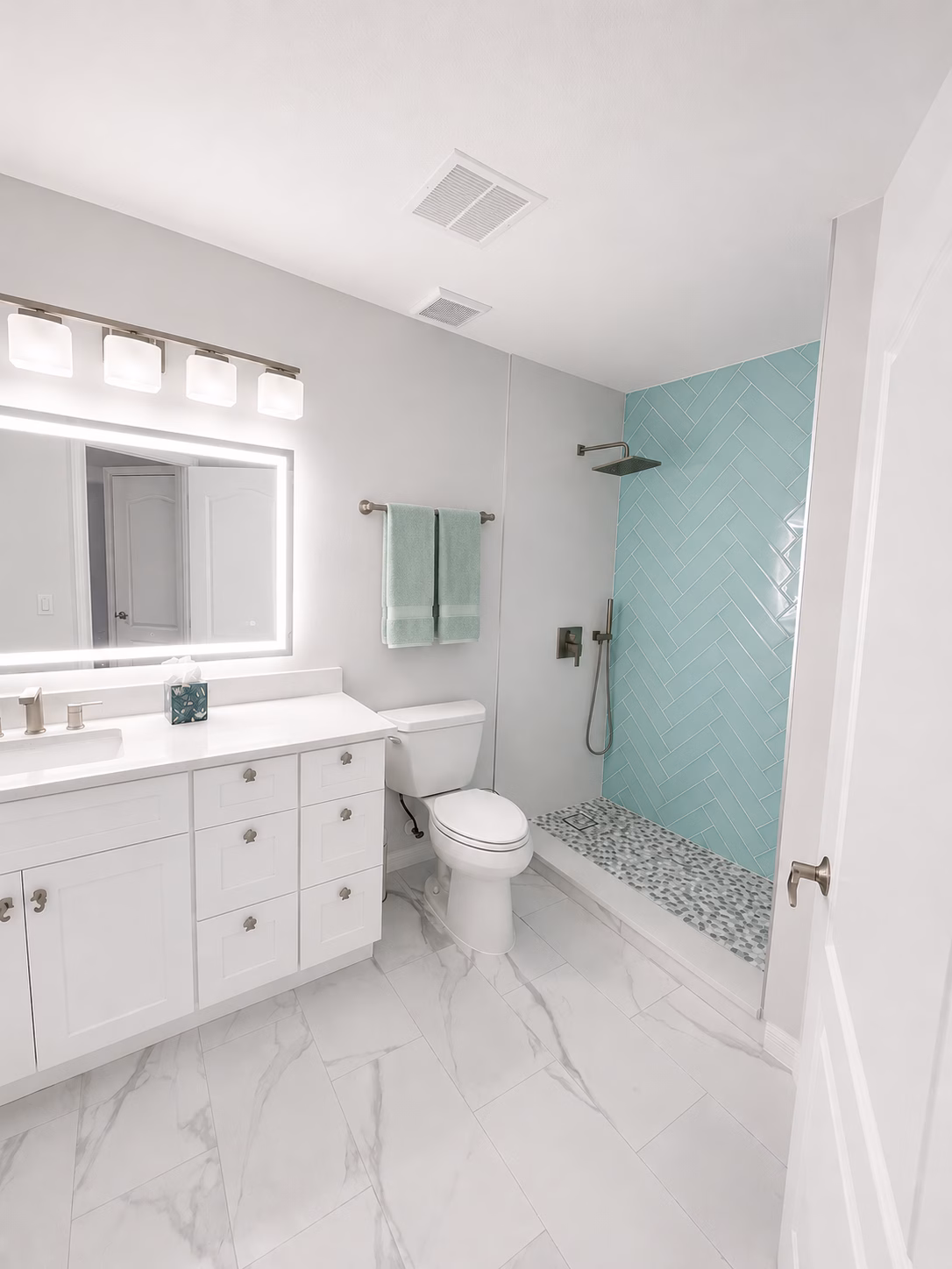Walk-in shower with an aqua tile wall and pebble floor, remodeled by BFM Builders