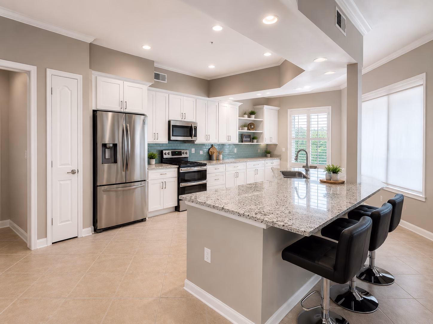 White kitchen with a green tile backsplash and a breakfast bar with three stools, remodeled by BFM Builders
