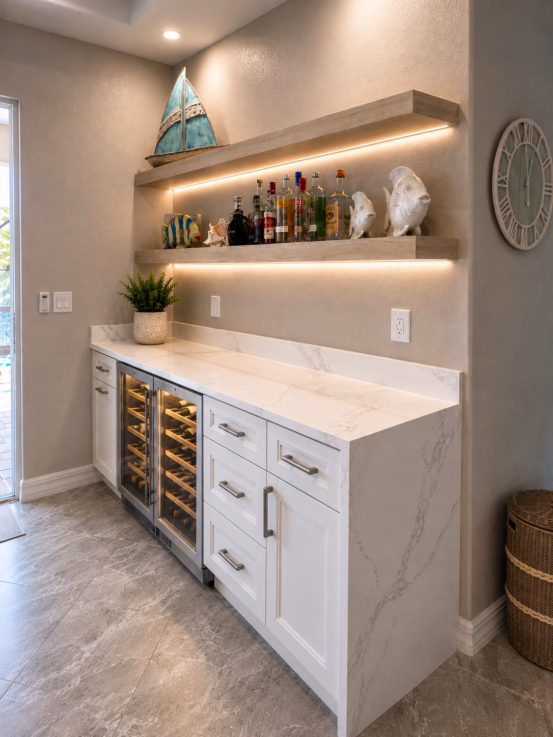 Built-in dry bar with a wine cooler, white cabinets and lit floating shelves, remodeled by BFM Builders