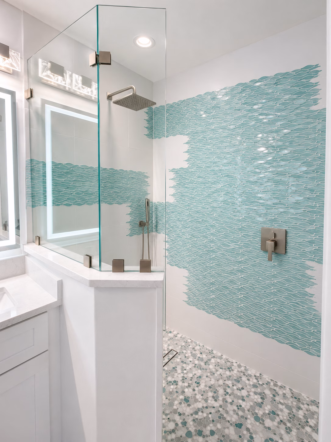 Shower with aqua glass mosaic tile, frameless glass and a pebble floor, remodeled by BFM Builders