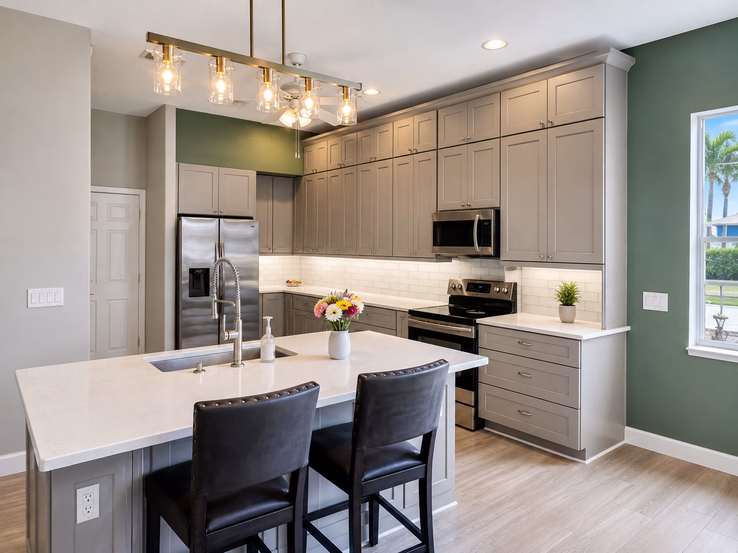Gray shaker kitchen with a white island, subway tile backsplash and pendant lights, remodeled by BFM Builders