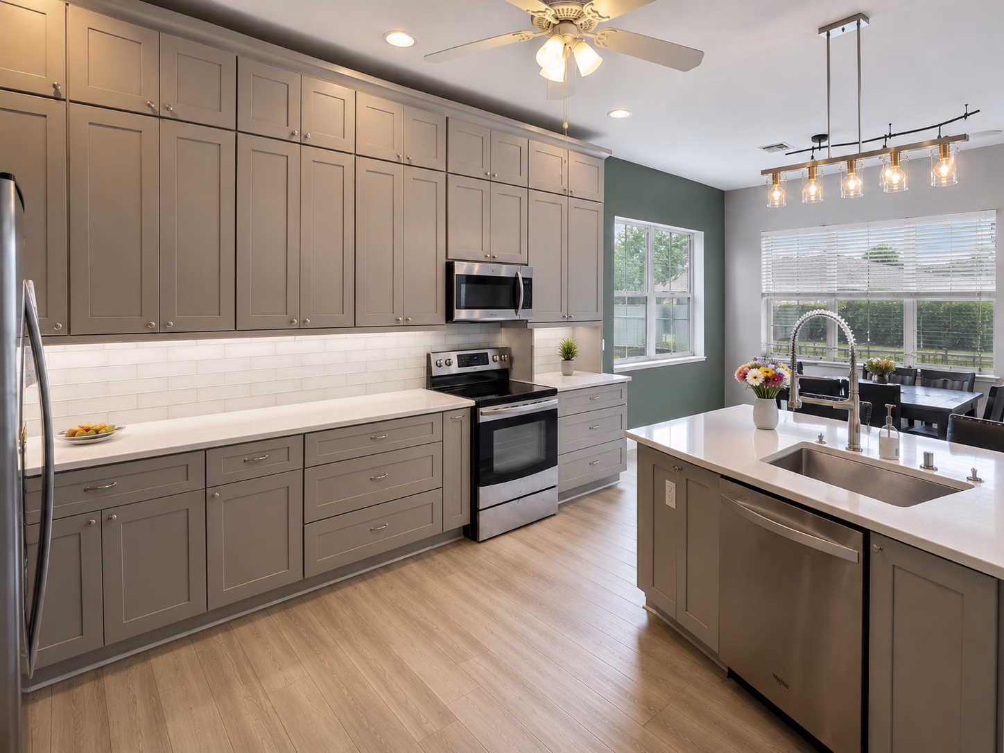 Gray shaker cabinets to the ceiling and a white island with pendant lights, remodeled by BFM Builders