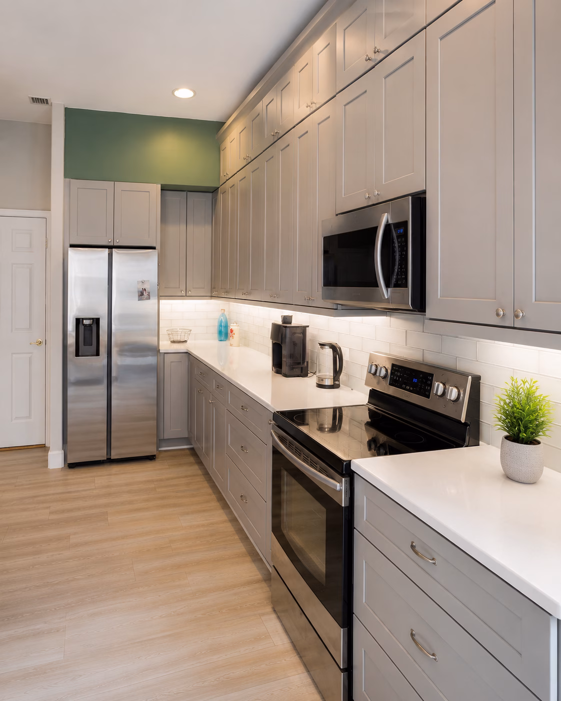 Gray shaker kitchen with tall cabinets, subway tile backsplash and stainless steel range, remodeled by BFM Builders
