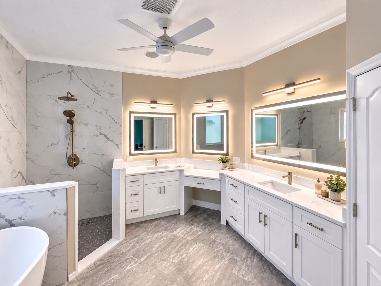 Double vanity with a makeup counter and backlit mirrors in a marble-look master bathroom remodeled by BFM Builders