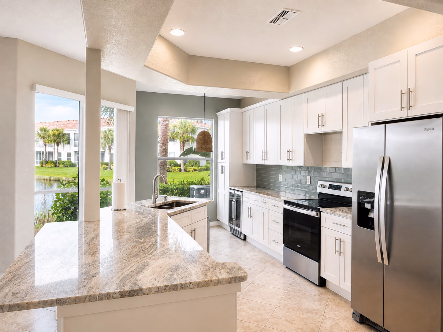 Open-concept kitchen with a granite peninsula, white cabinets and stainless steel appliances, remodeled by BFM Builders