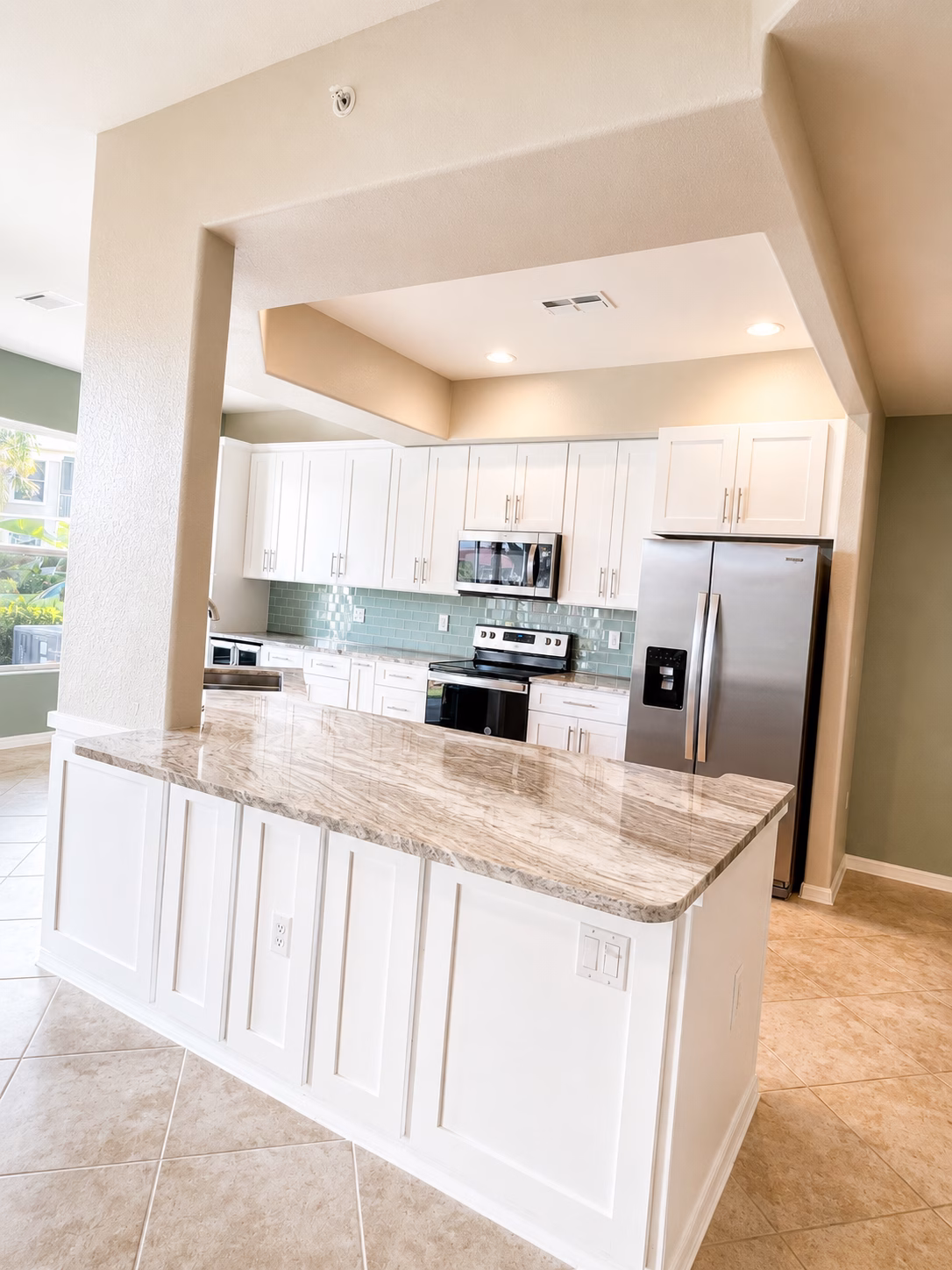 Kitchen opened to the living area with a white island and granite countertop, remodeled by BFM Builders