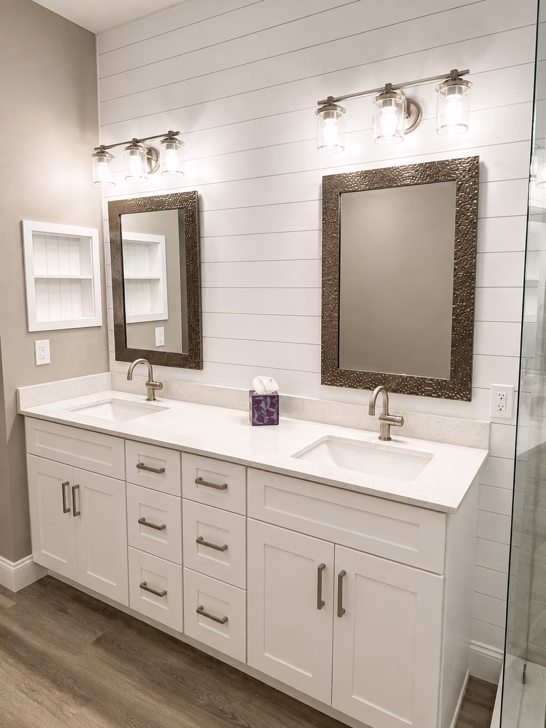 White double vanity under a shiplap wall with framed mirrors and sconces, remodeled by BFM Builders