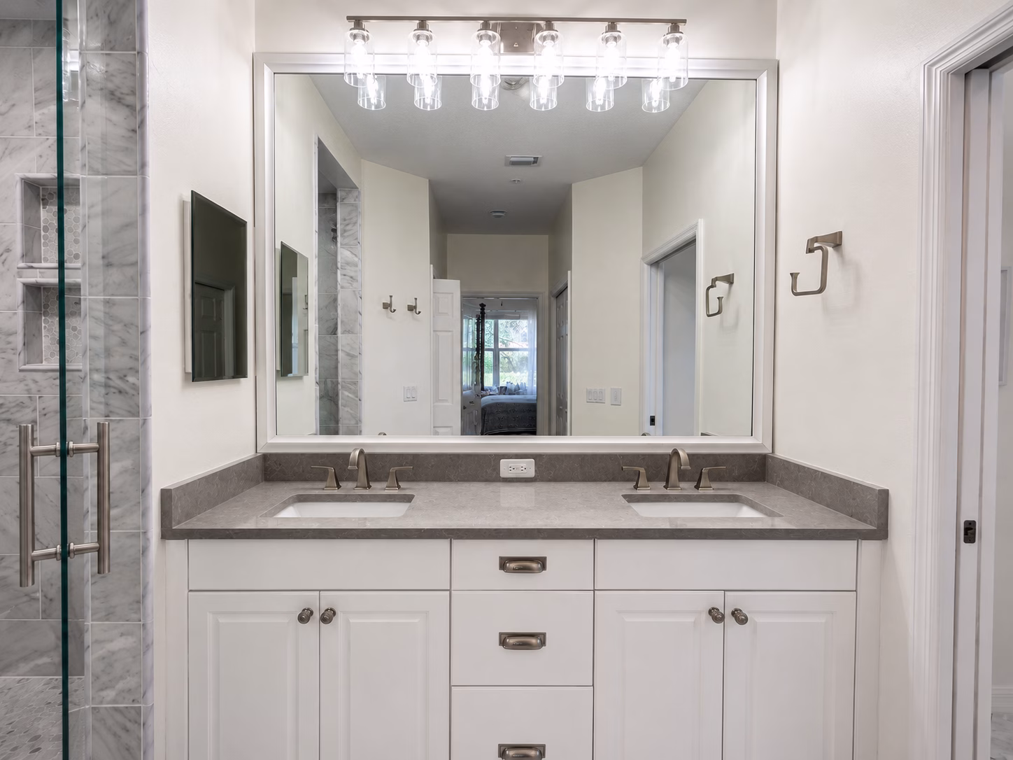 Double vanity with a gray countertop and a large framed mirror in a bathroom remodeled by BFM Builders