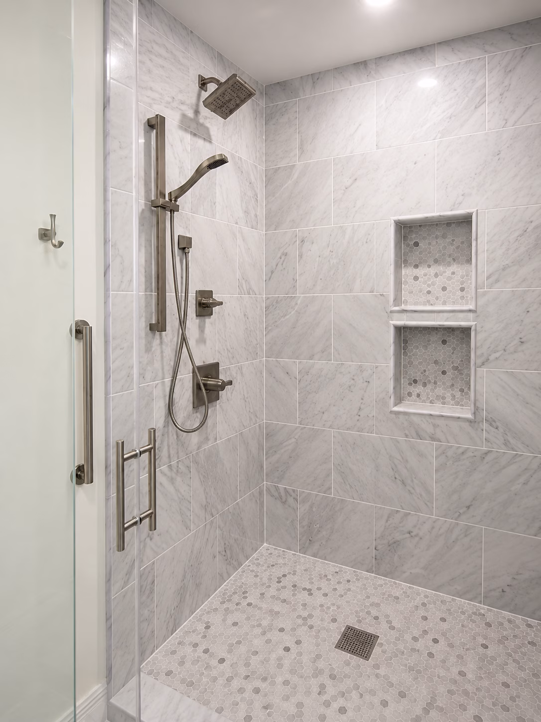 Walk-in shower with gray tile walls, two niches, grab bar and handheld shower, remodeled by BFM Builders